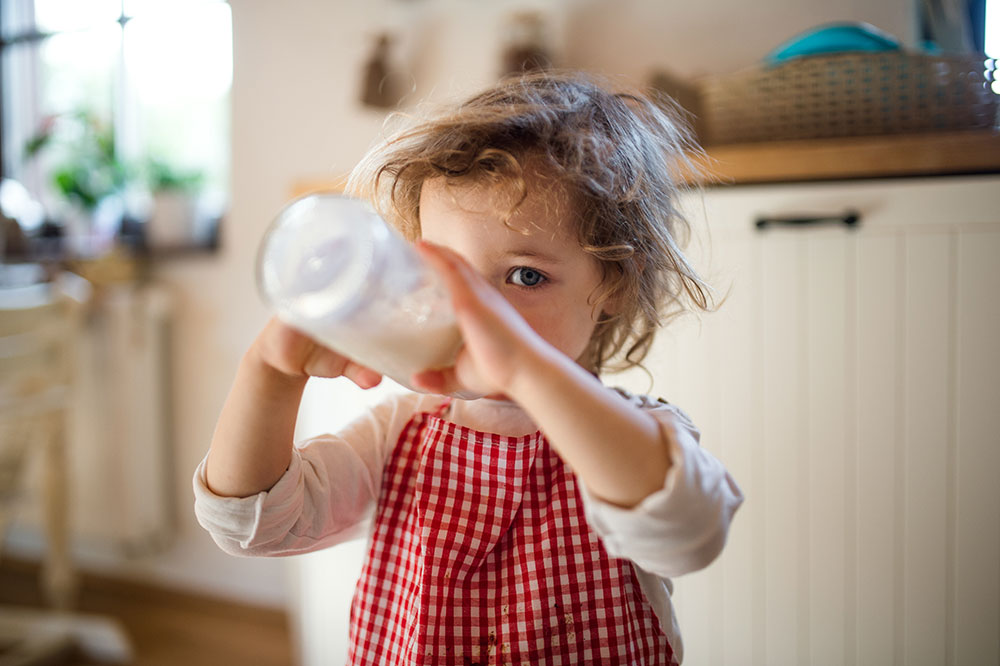 Toddler girl drinking from a bottle.